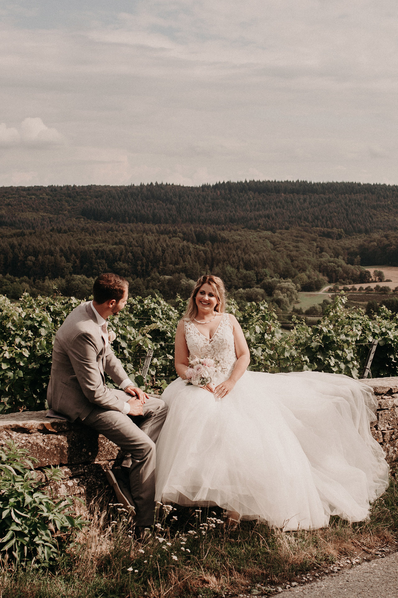 Braut und Bräutigam sitzen auf einer Wiese – verträumte Hochzeitsfotos in der Natur