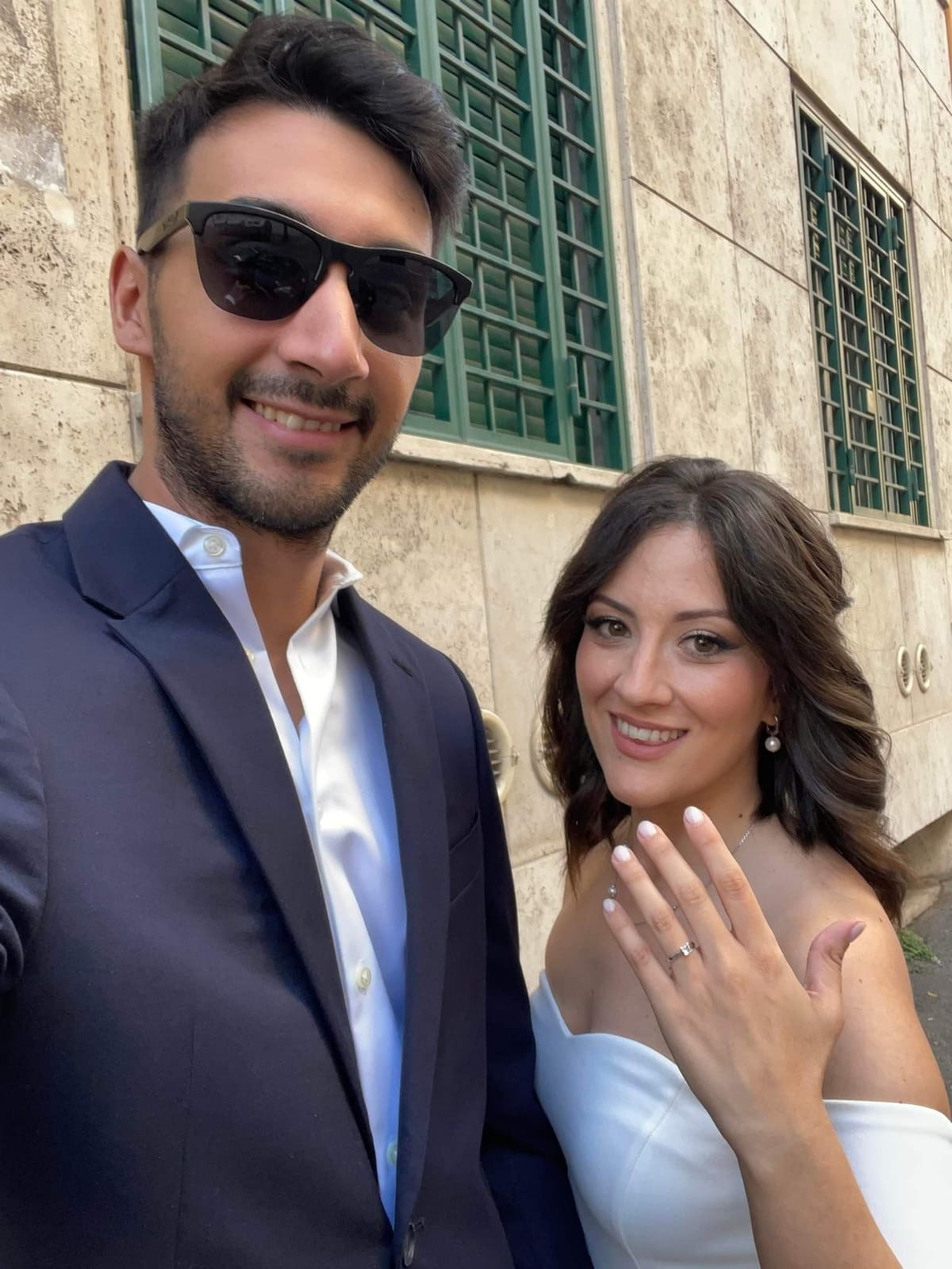 a bride and a groom posing with a hand in front showing her ring