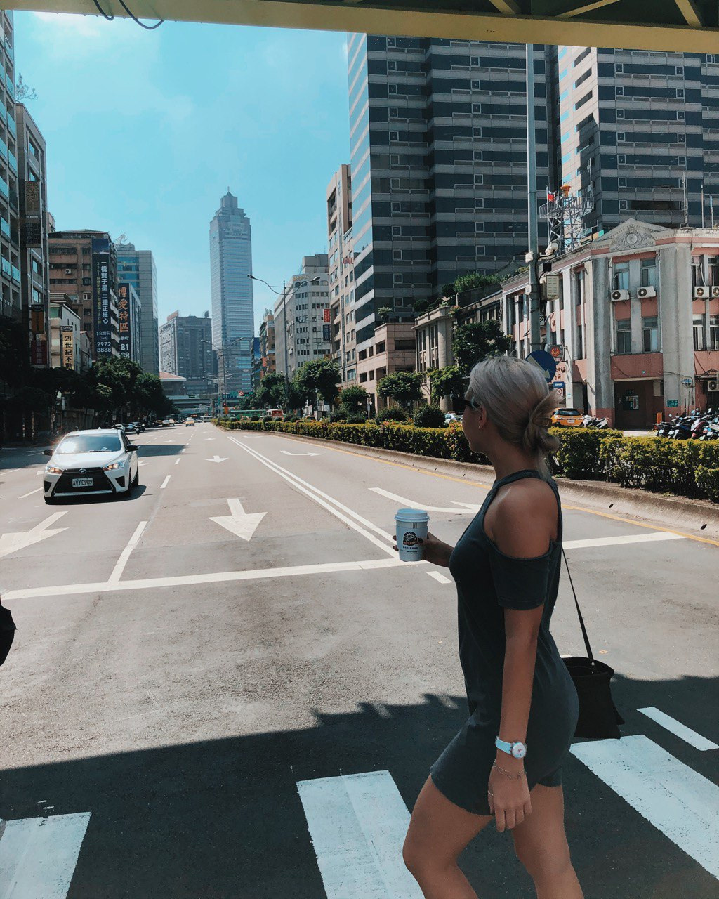 a girl crossing a street in taiwan with coffe cup in a hand