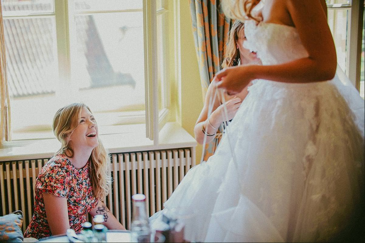 Bride’s best friend helping her put on wedding shoes