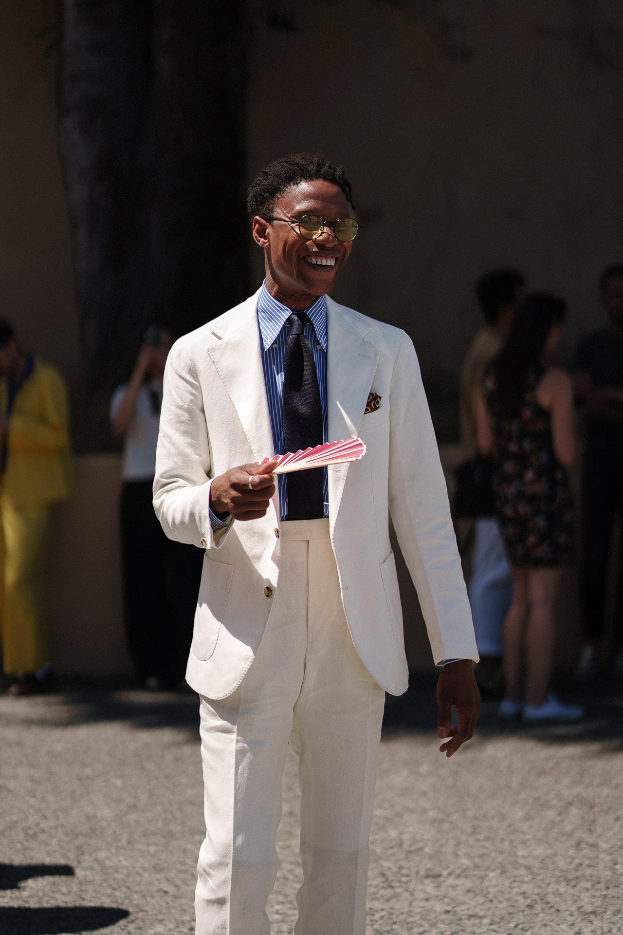 Ospite di Pitti Uomo 110 in completo estivo bianco con ventaglio fuori dalla Fortezza da Basso