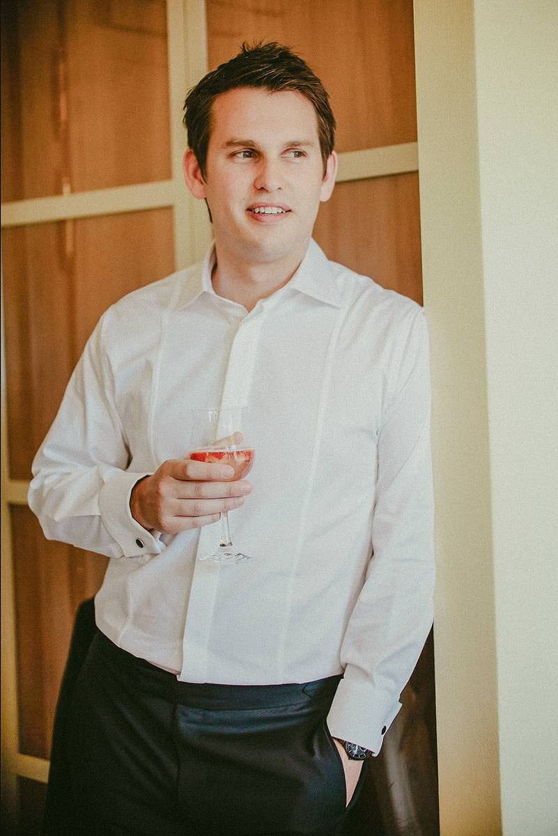 Groom Dan smiles while watching his bride get ready in the suite