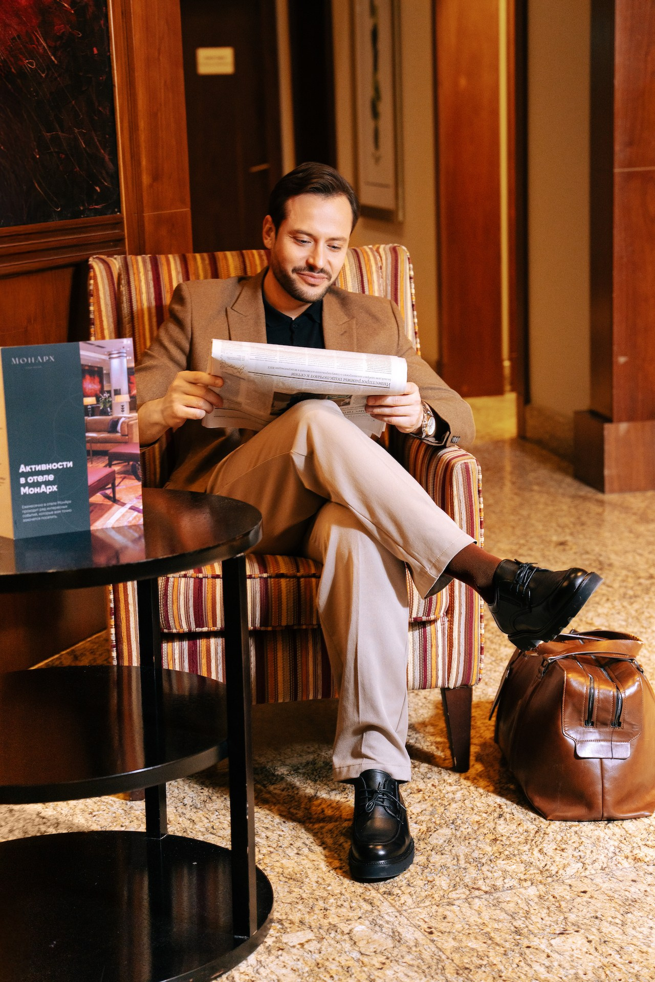 Гость в пиджаке листает журнал в лаунж-зоне отеля