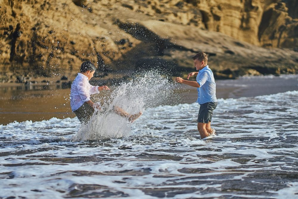 Sesión de comunión en la playa en Tenerife, niños jugando con el agua