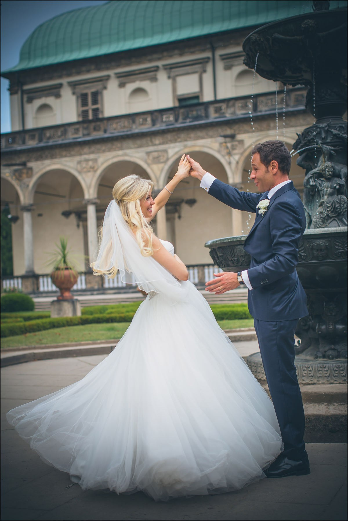 Groom spinning bride against palace backdrop Prague portrait session