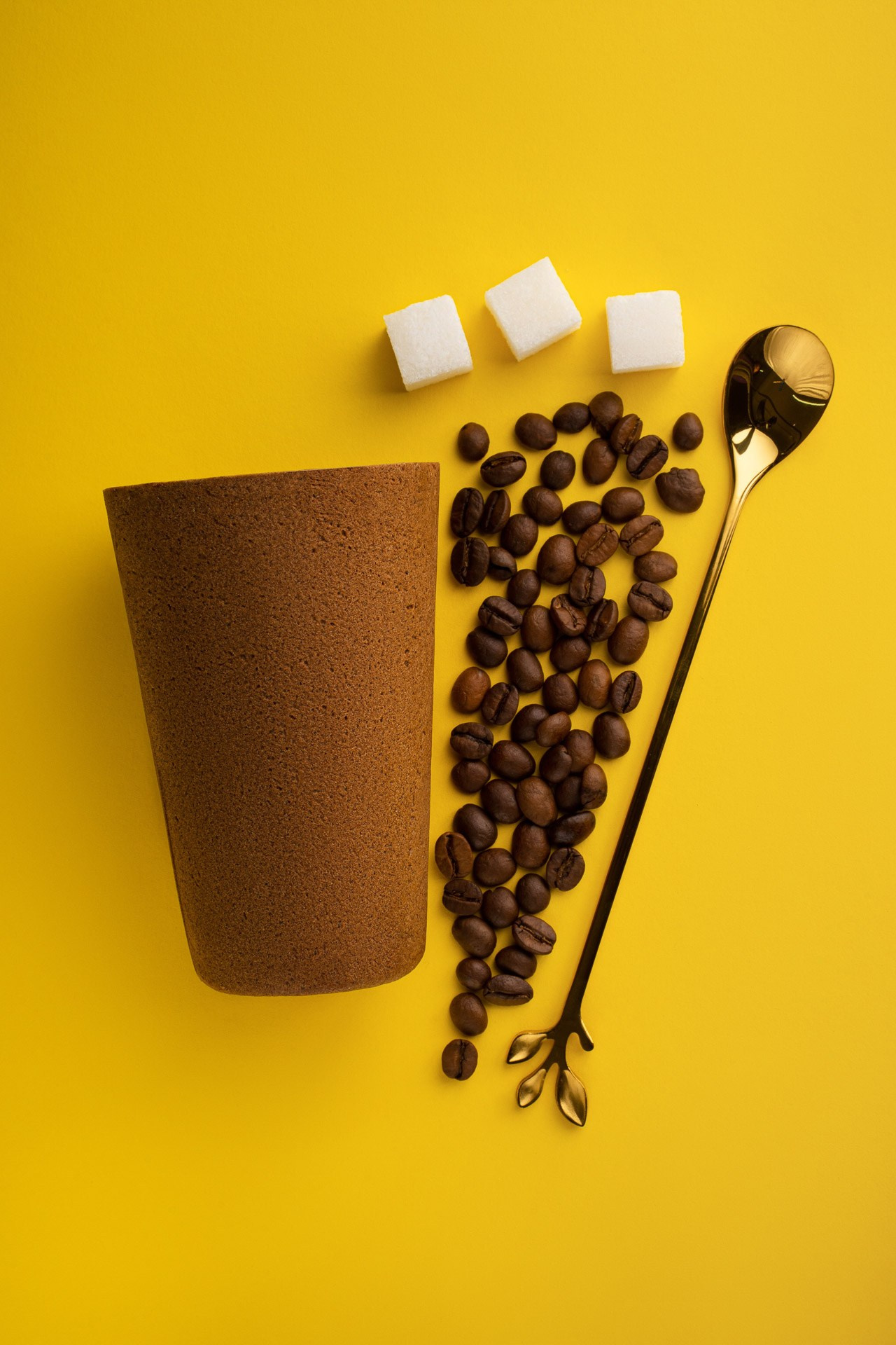 Minimal product flat lay with coffee beans and cup on yellow background