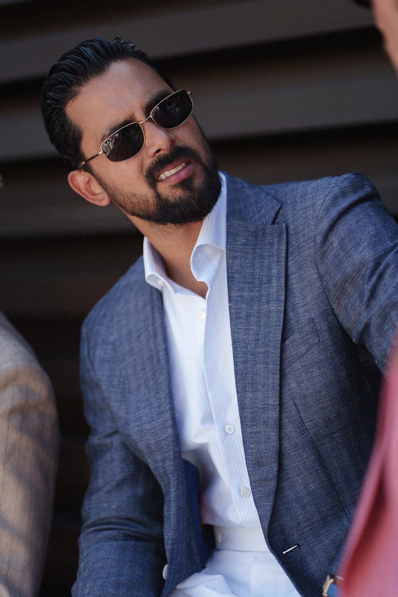 Ritratto menswear da Pitti Uomo 110, ospite in blazer blu e camicia bianca con occhiali da sole