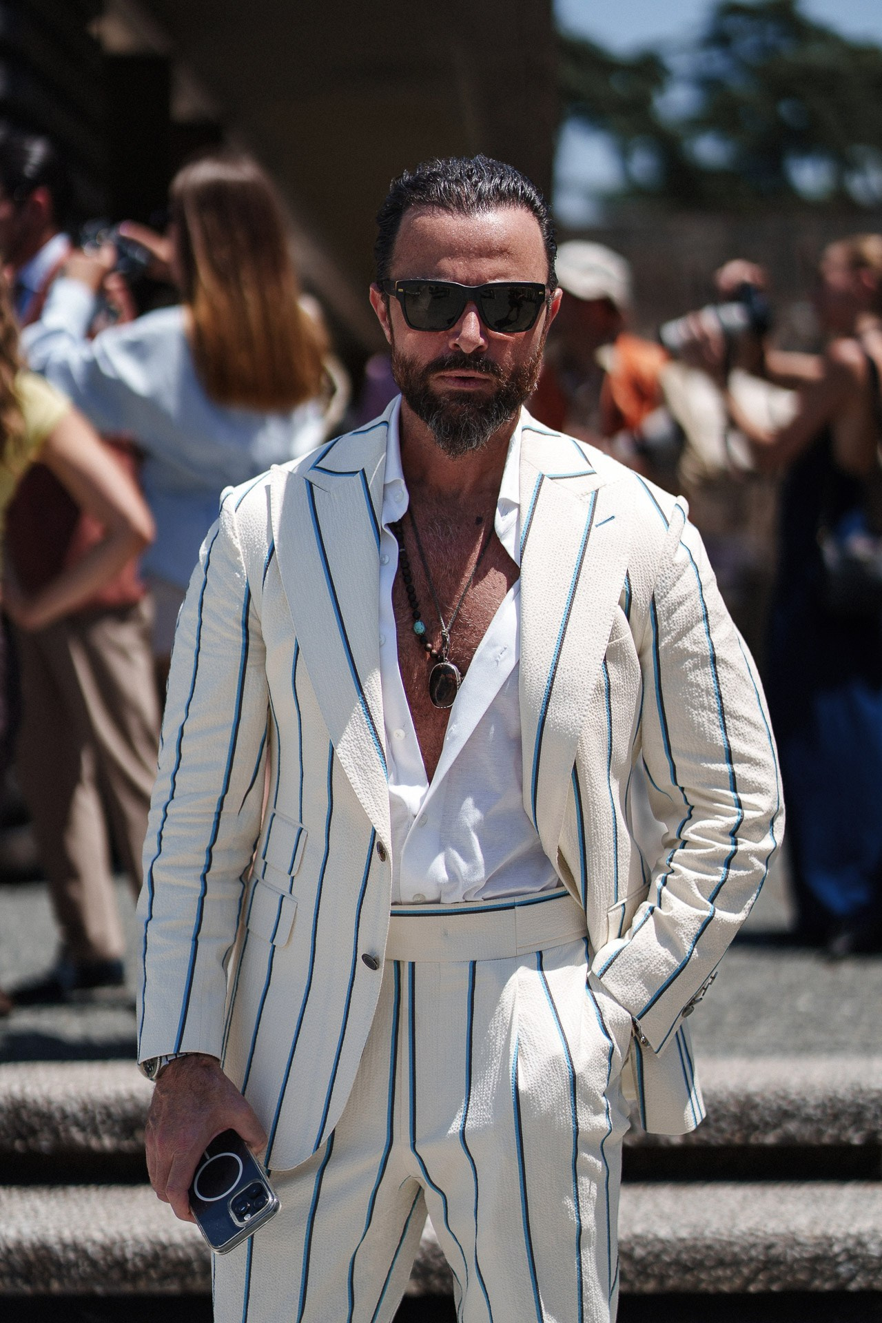 Ritratto street style da Pitti Uomo 110, uomo in completo bianco gessato con camicia aperta e occhiali da sole