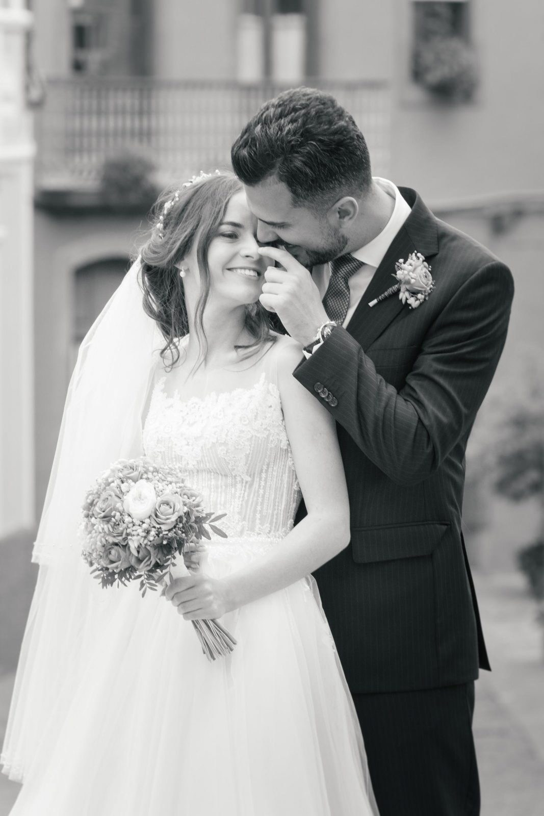 Une mariée et un marié s'embrassent devant un bâtiment.