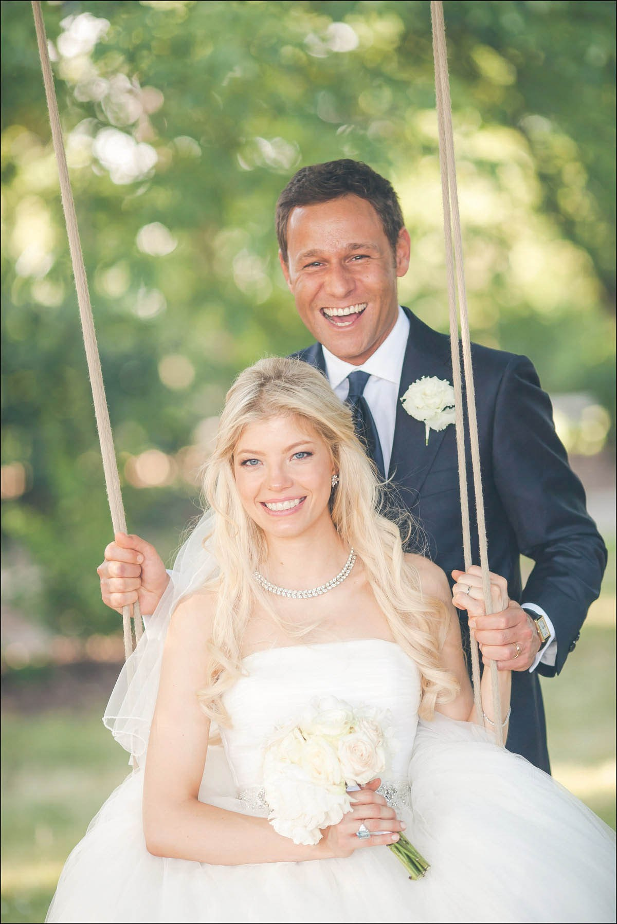 Bride on garden swing with groom behind at Prague Castle grounds