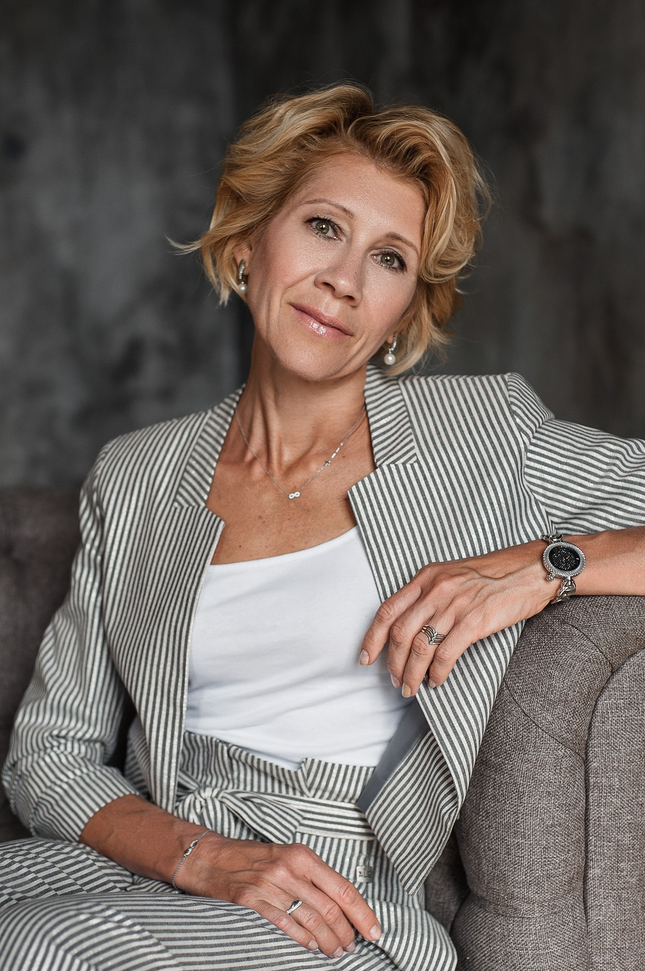 Professional executive business portrait of a woman in a striped blazer sitting on a sofa in a Milan office.