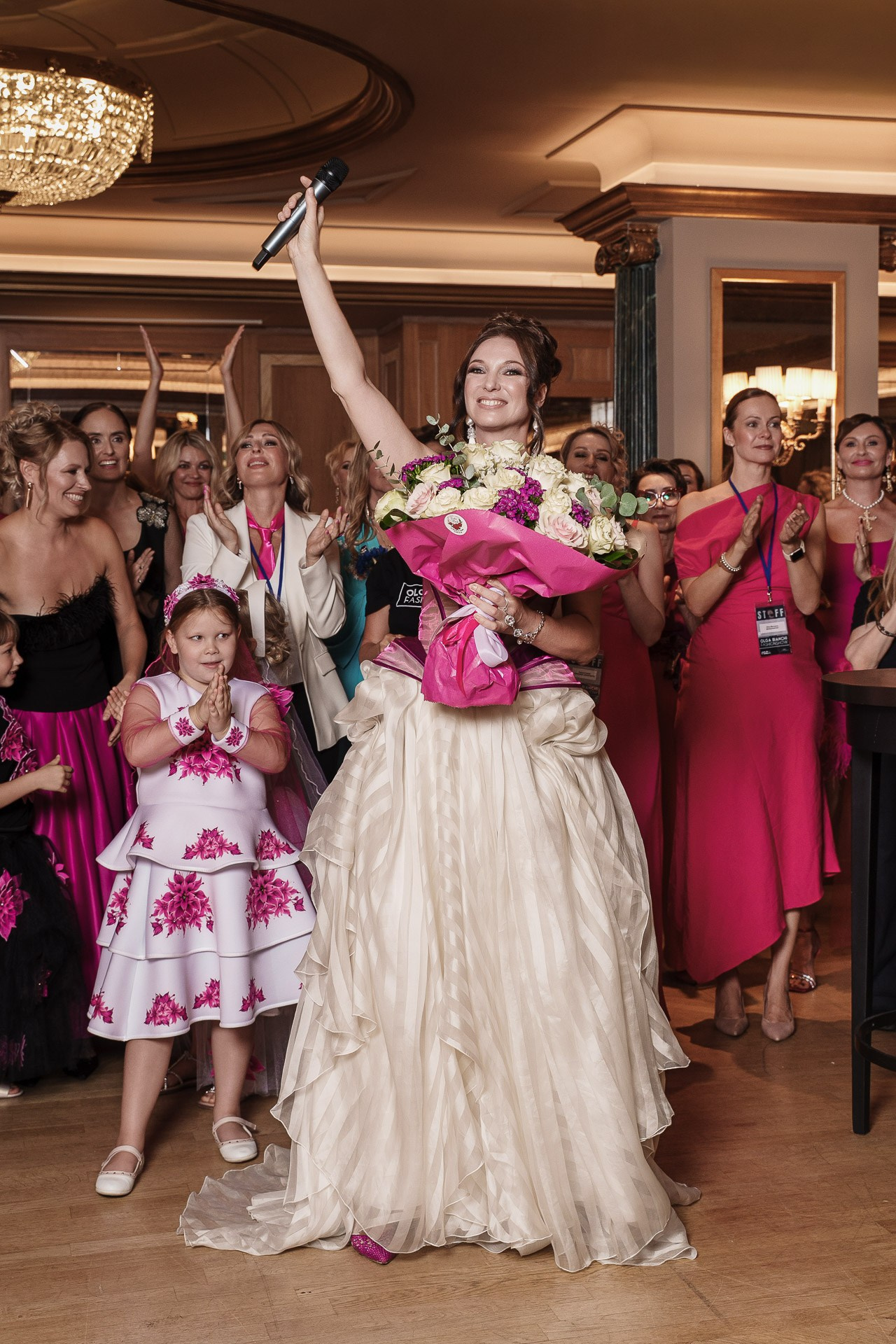 Award ceremony host celebrating on stage with a bouquet during a corporate gala event in Milan.