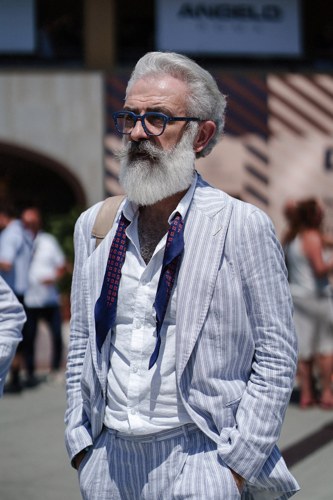 Ritratto street style da Pitti Uomo 110, ospite con barba in completo azzurro a righe e occhiali