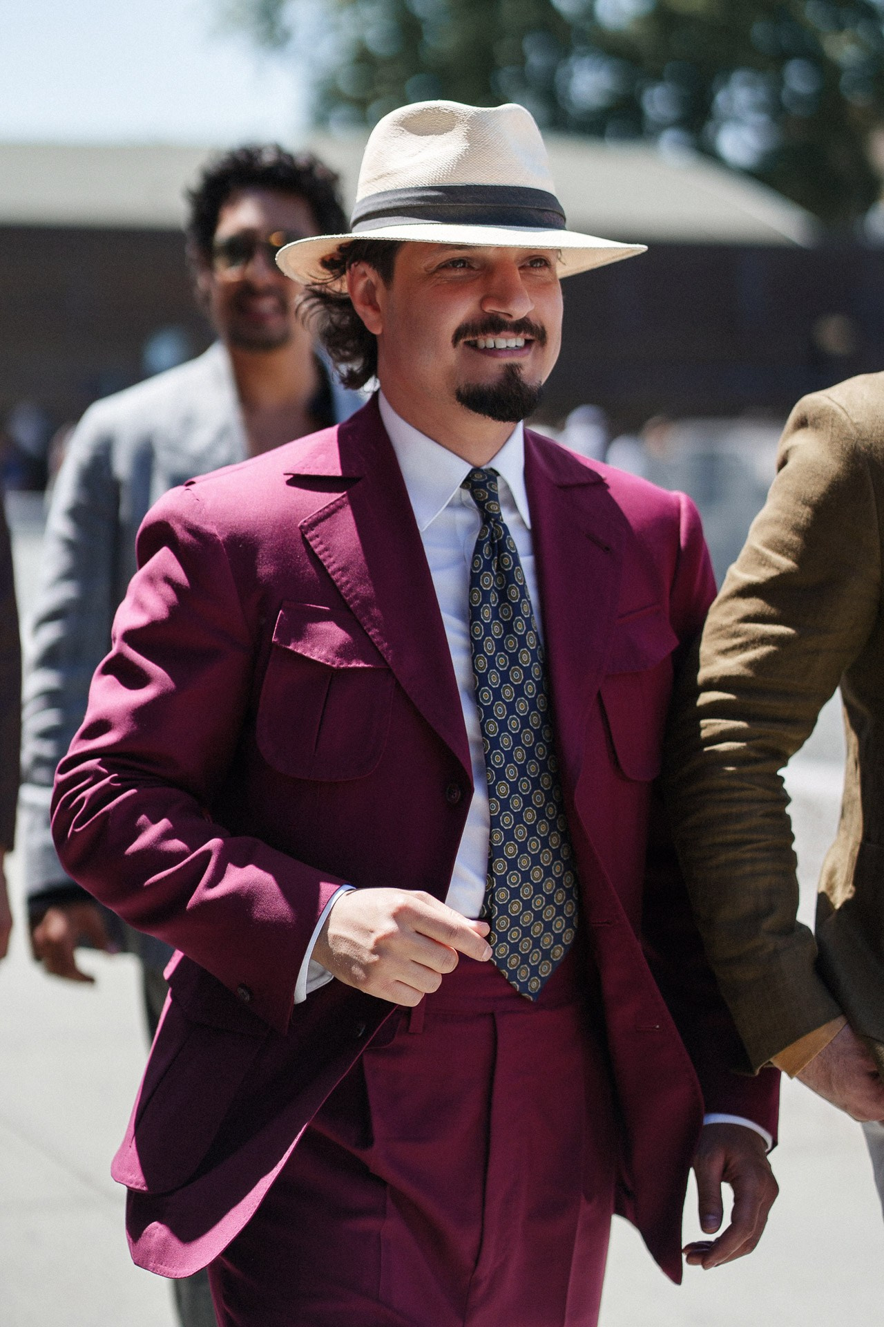 Ospite di Pitti Uomo 110 in completo sartoriale bordeaux e cappello di paglia vicino alla Fortezza da Basso