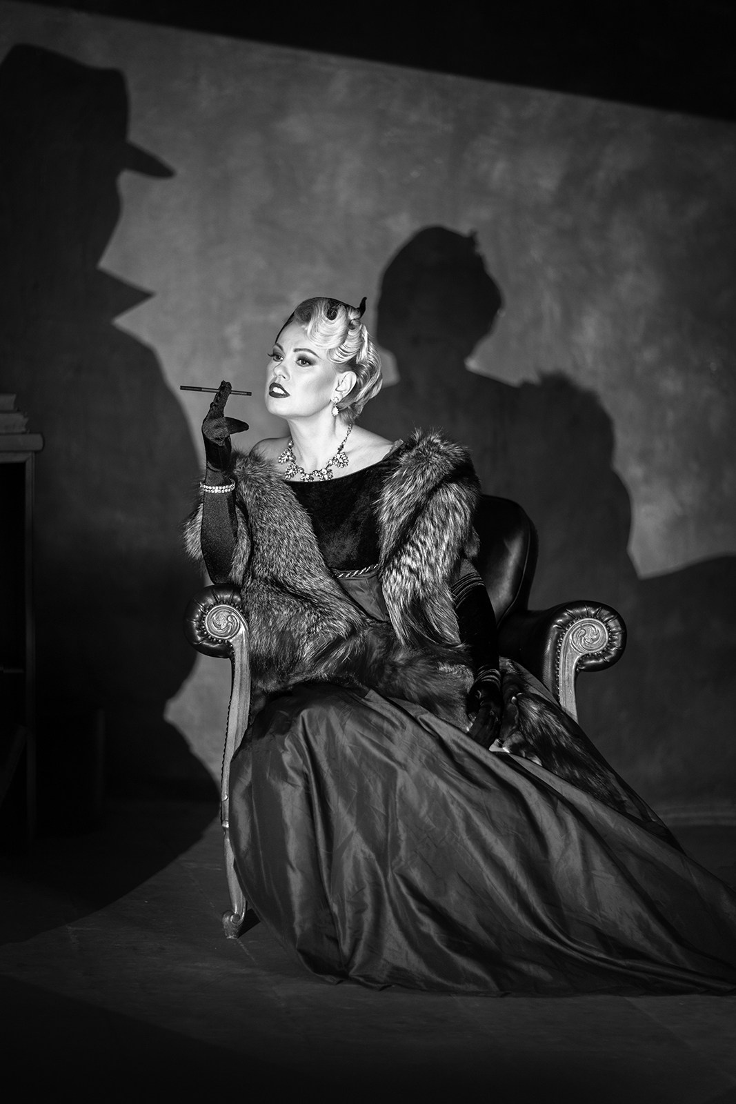 Арт-фотография женщины в винтажном платье с театральной тенью на стене