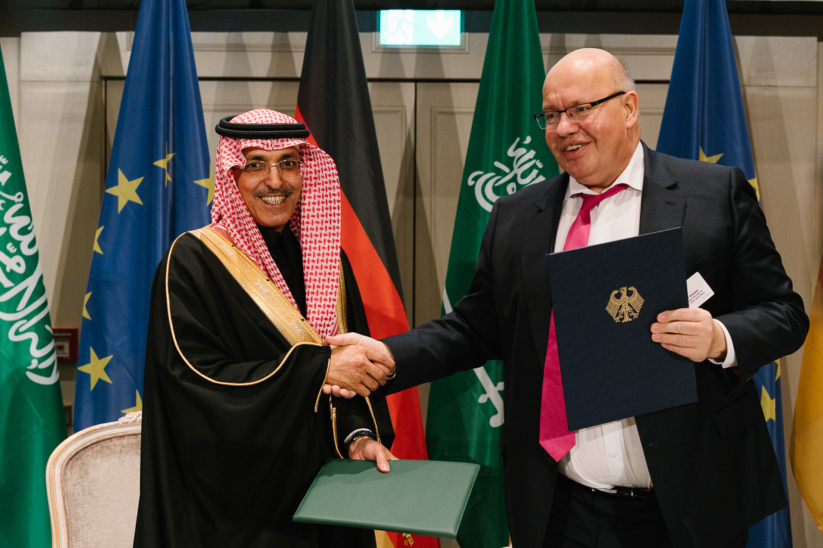Signing ceremony with two officials shaking hands in front of international flags, captured by the event photographer in Berlin