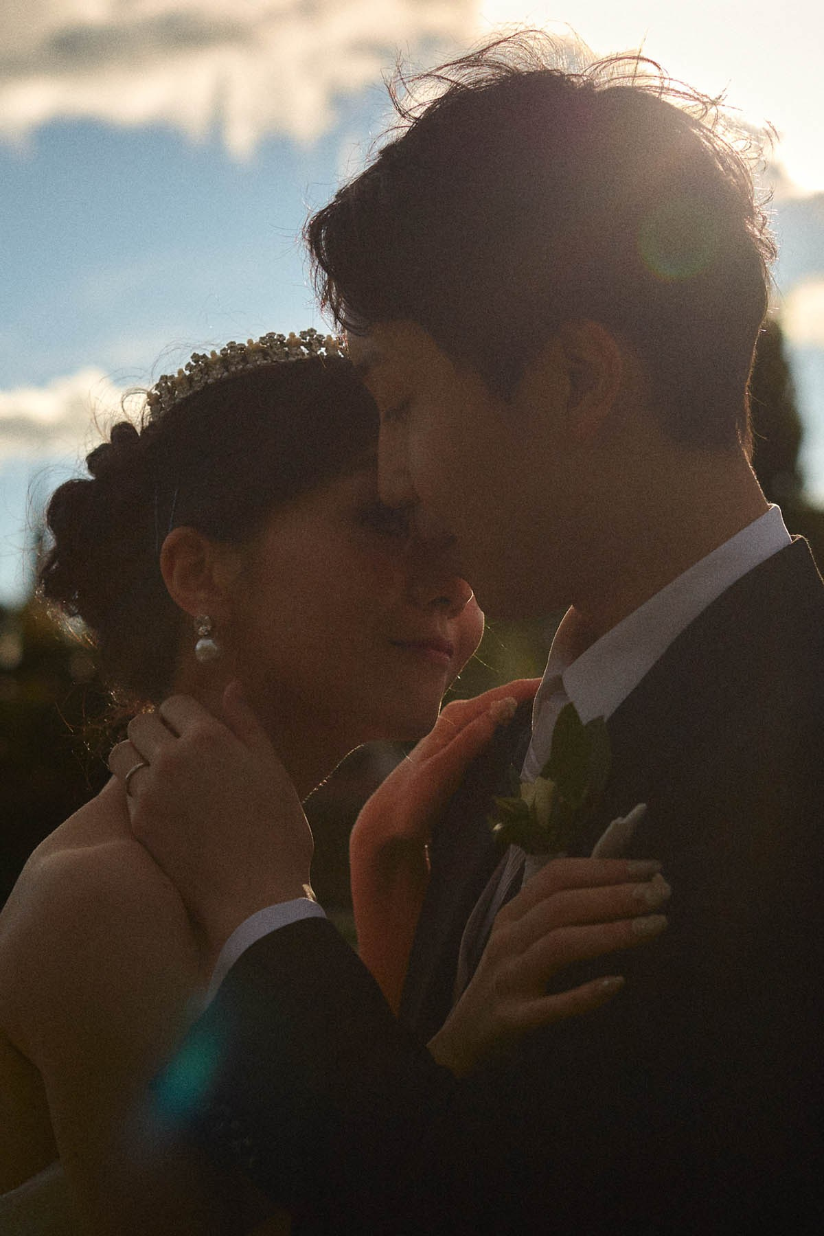 Newlyweds silhouetted embrace with sun rim light in the Belvedere gardens.