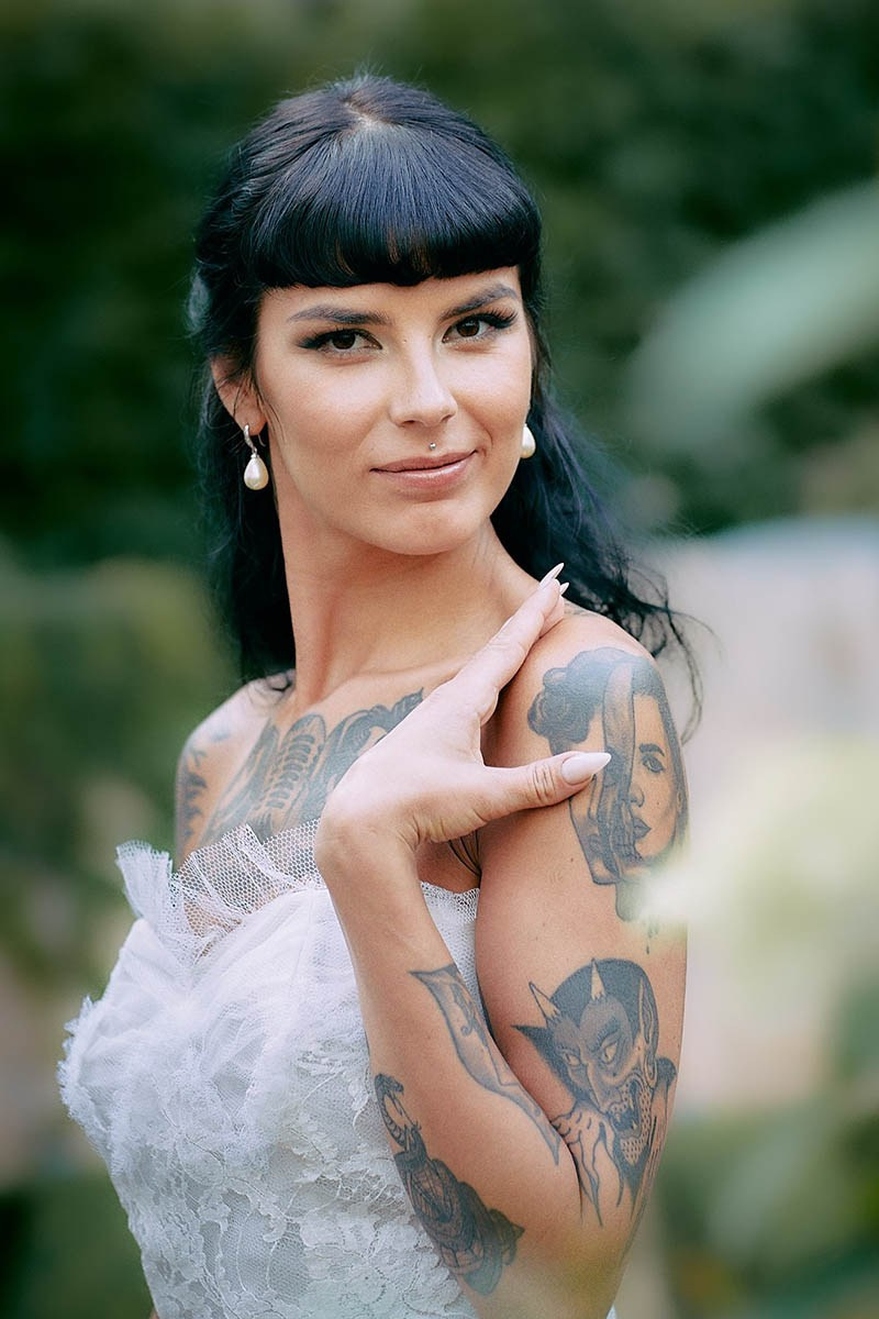 Burlesque bride confident, striking pose in luxurious hotel garden.