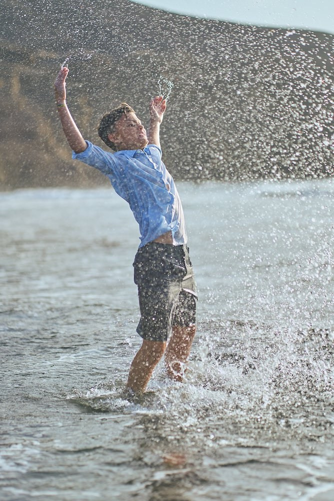 Comunión en la playa con luz natural, niño disfrutando del mar