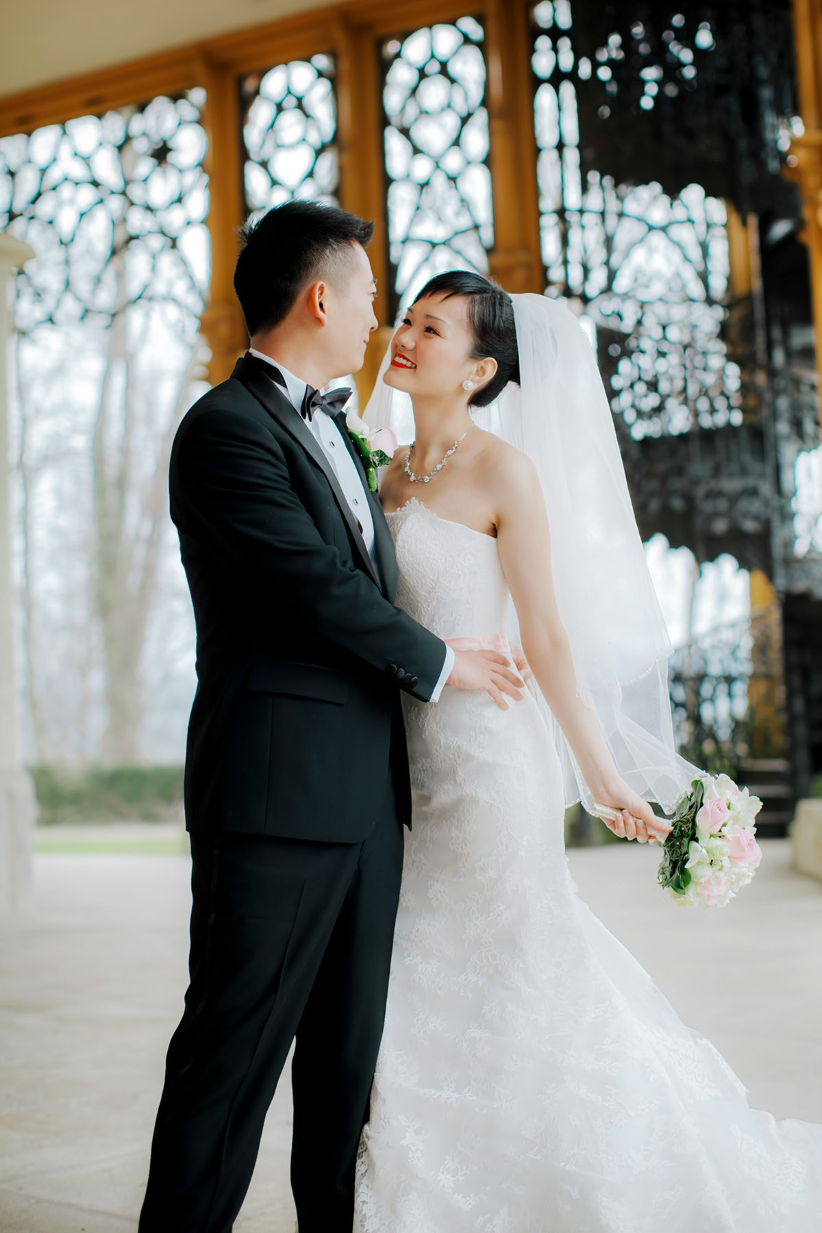 A radiant Hong Kong bride snuggles with her tuxedo wearing groom  on the historic grounds of Castle Hluboka during their destination wedding in Czechia.