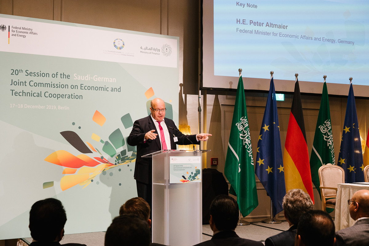 Keynote speaker at the podium during an international business conference with a projection screen