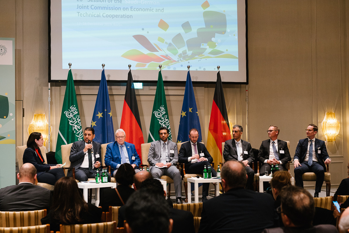 Panel discussion with speakers on stage in front of international flags at a business conference