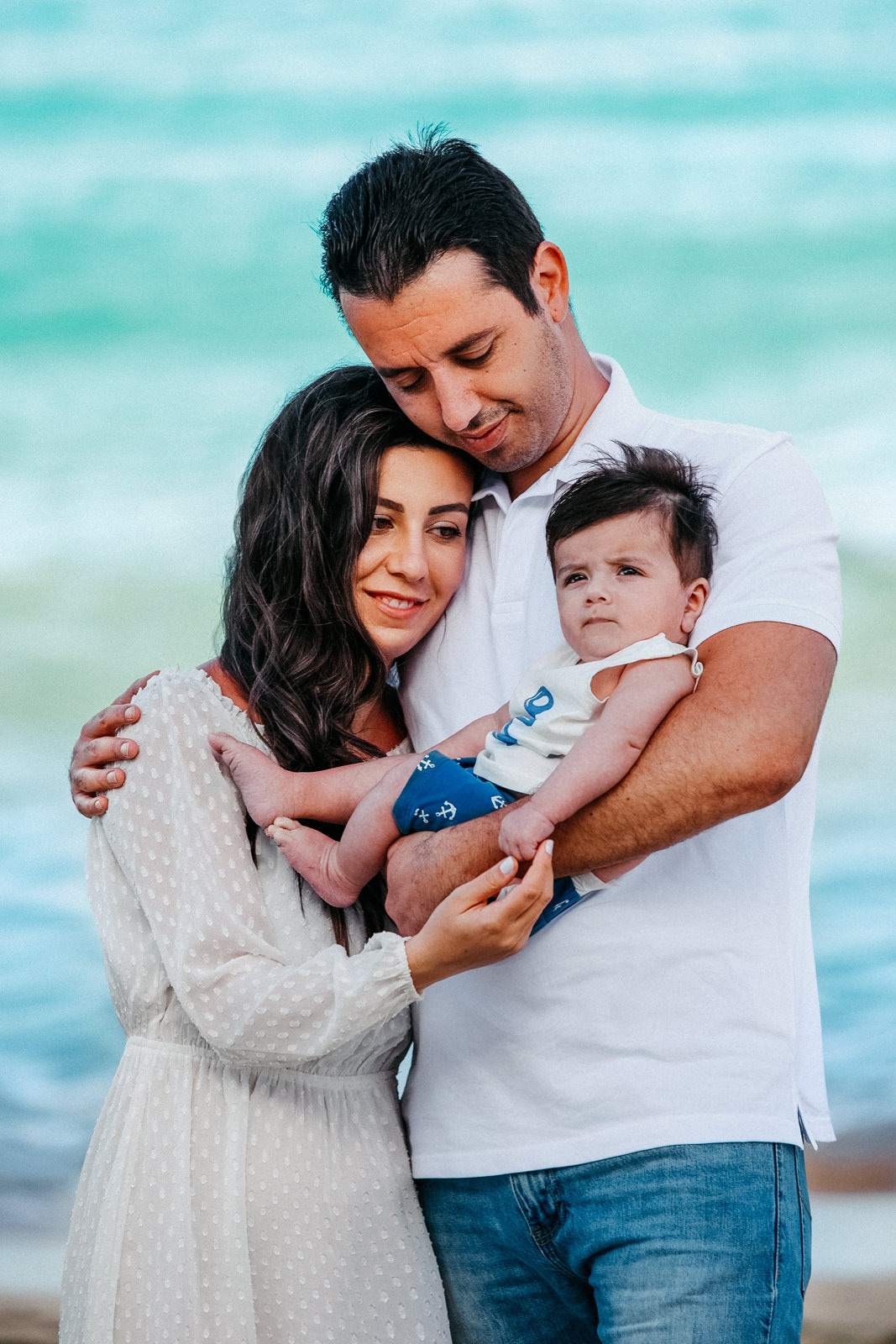 A man and woman holding a baby on the beach Amadores