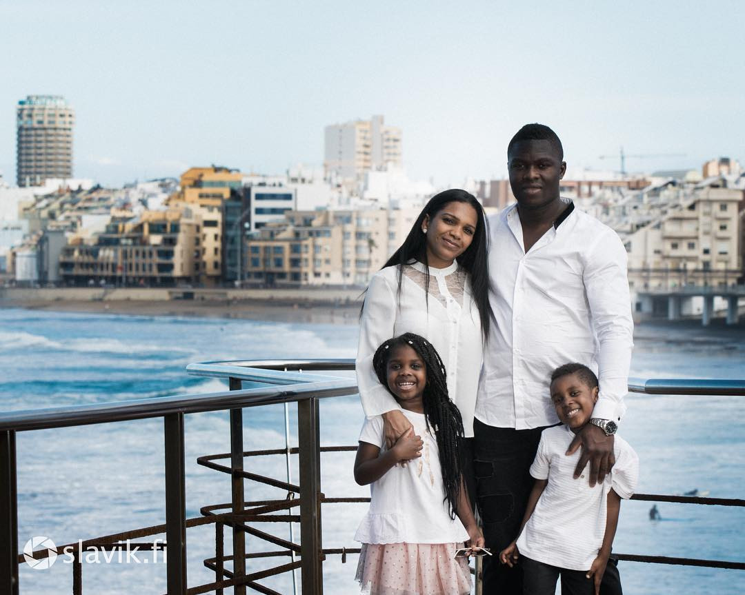A family is posing for a photo on a balcony overlooking the ocean Las Palmas