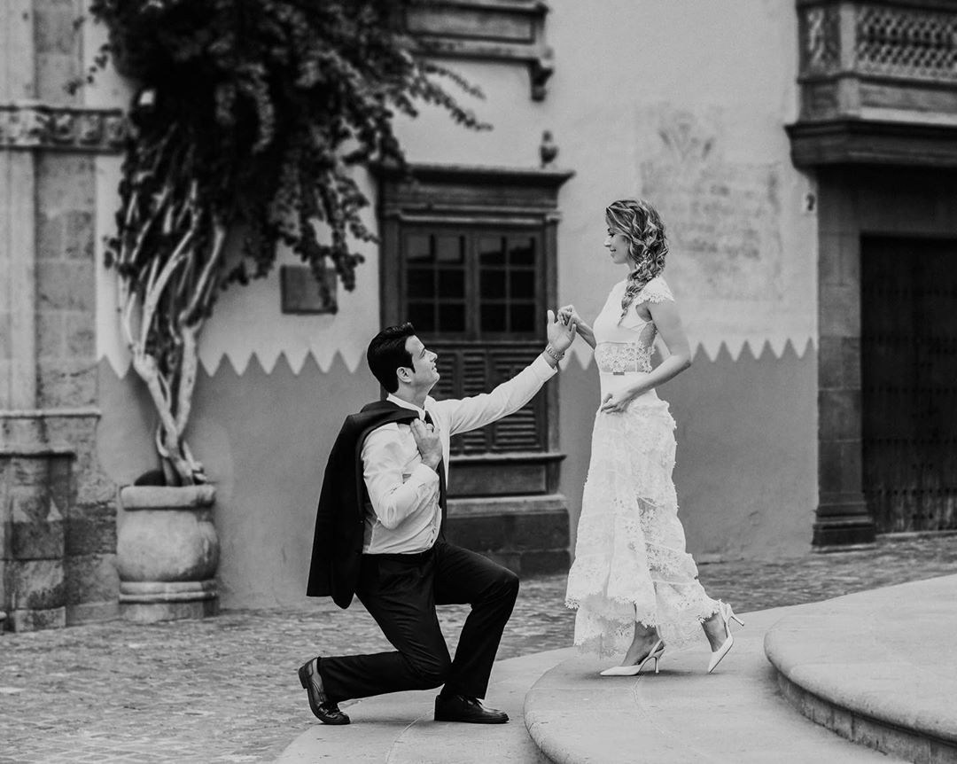 Une mariée et un marié agenouillés sur les marches devant un bâtiment.