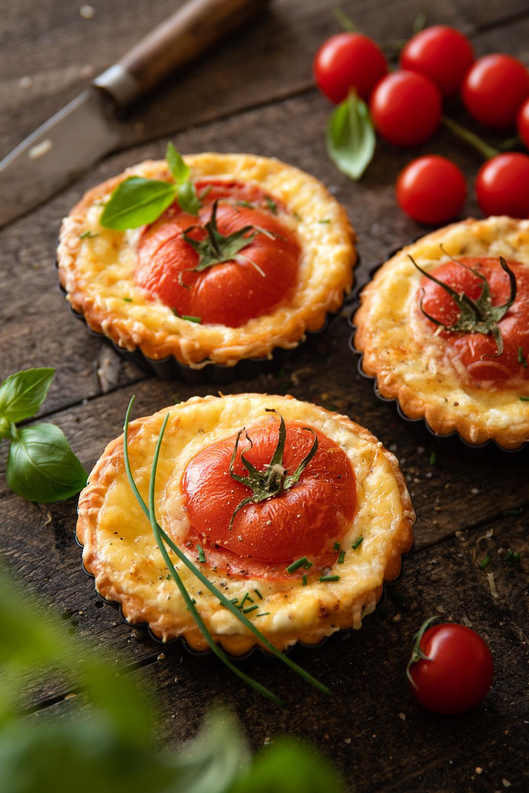 Ein leichter Snack - Pizzatarteletten mit Frischkäse, Ricotta , Schnittlauch, Thymian und Tomaten in Tartelettenform auf dem Holzbrett