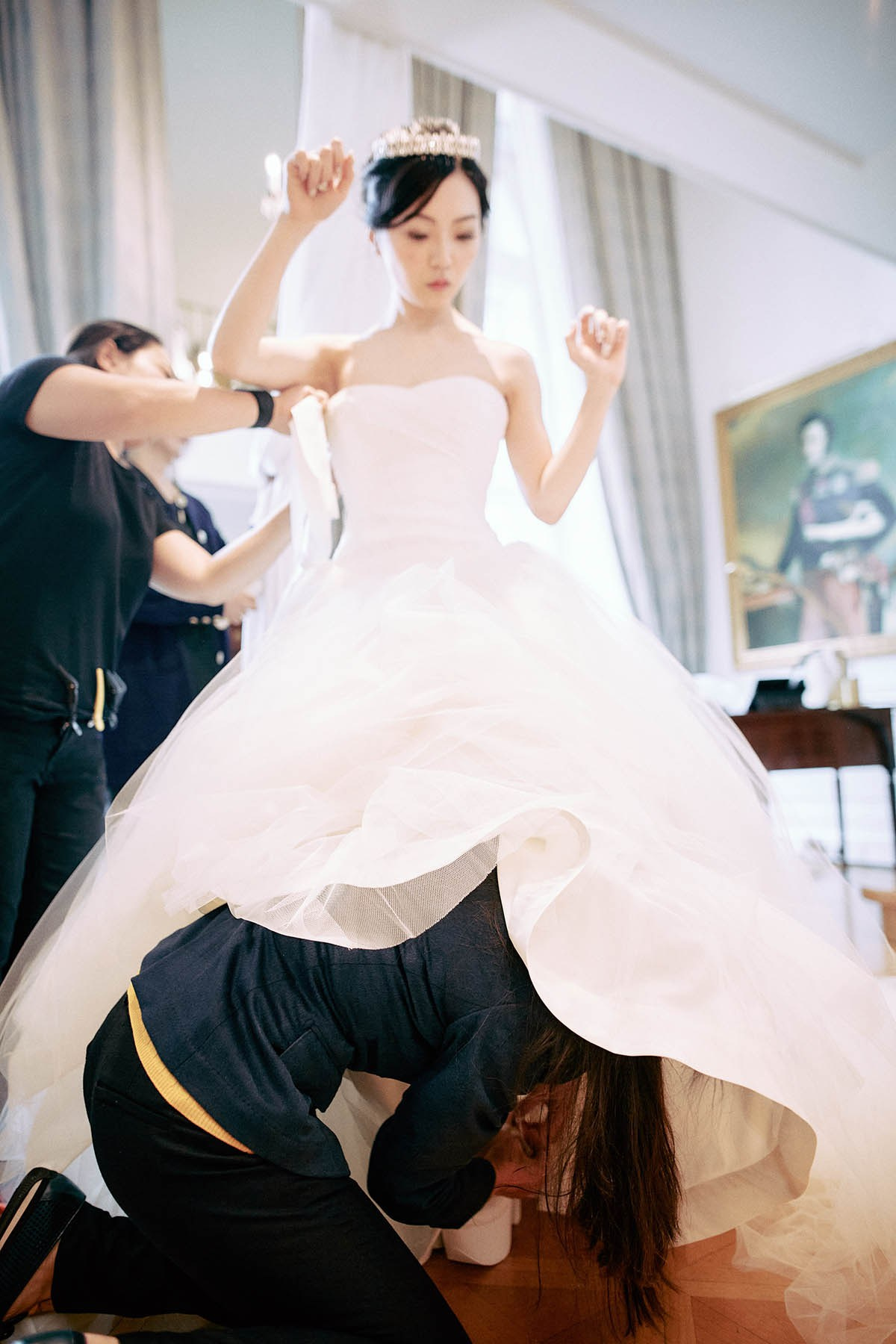 An assistant gets under the dress to put on her stylish shoes.