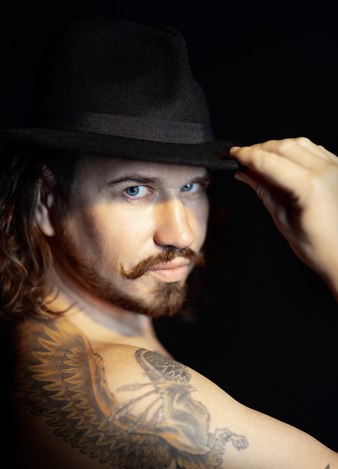 Портрет мужчины с татуировкой и чёрной шляпой, студийная фотосессия