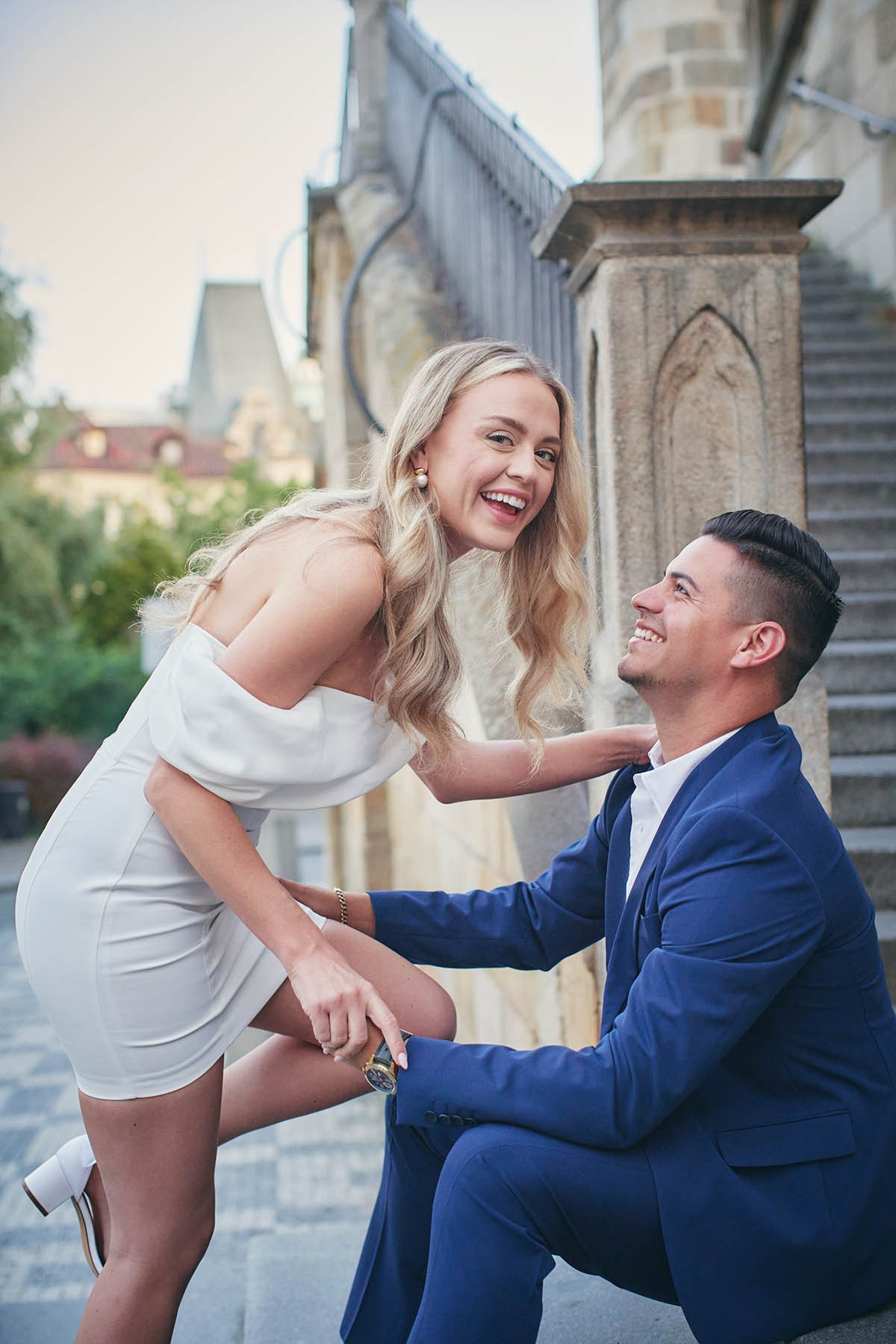 A young couple exchanging tender flirtation on the peaceful Kampa Island steps at dawn.