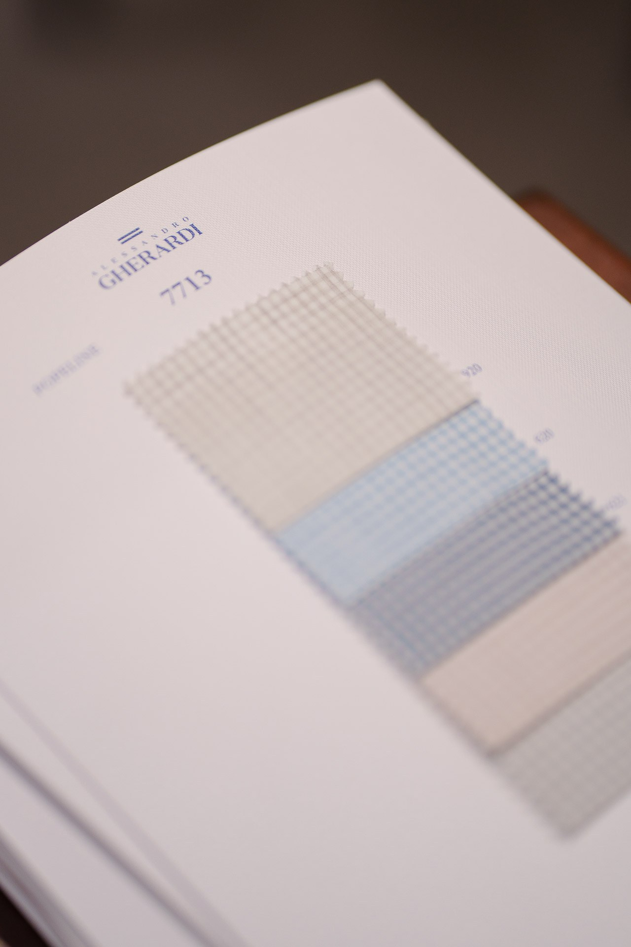 A fabric swatch book from Alessandro Gherardi showing various textile samples for custom tailoring