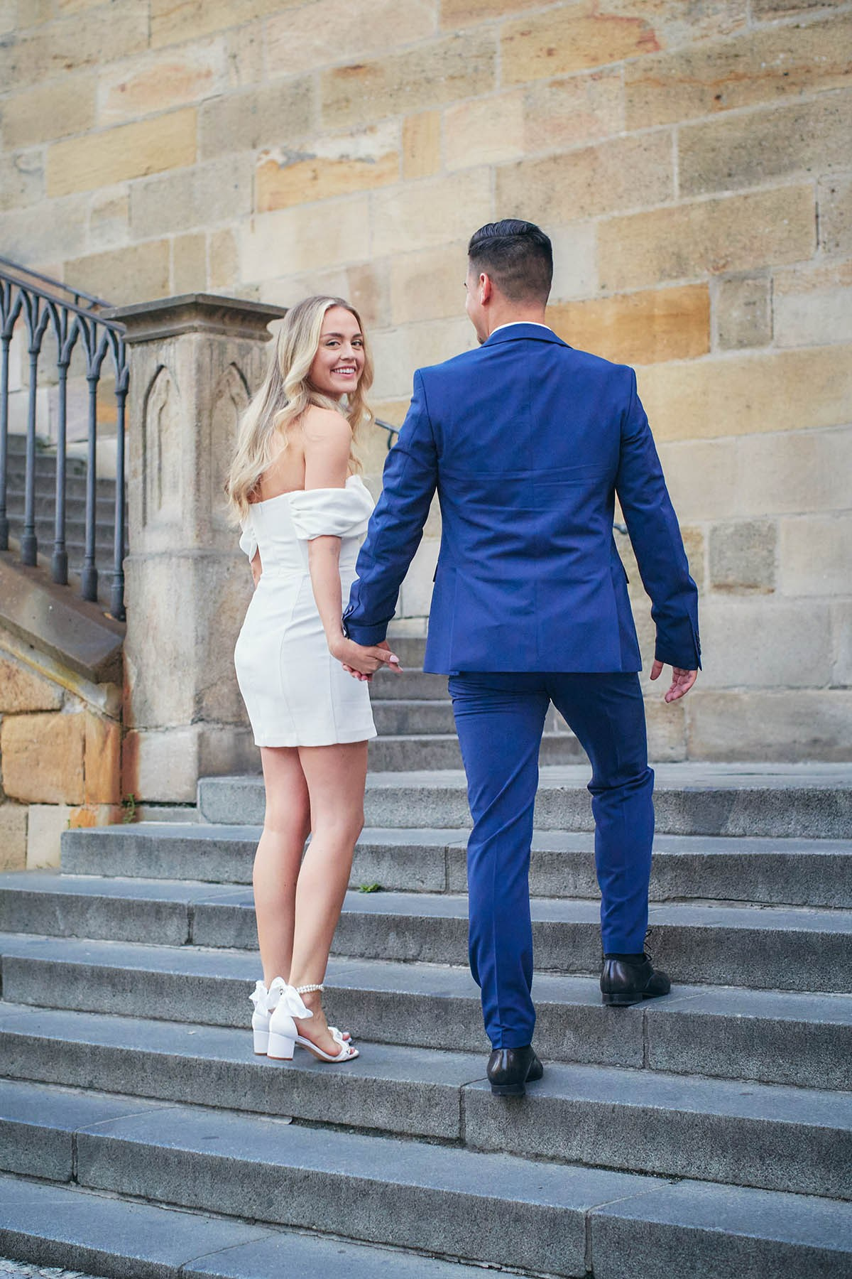 A flirty woman looks over her shoulder as she and her partner walk up the historic steps.