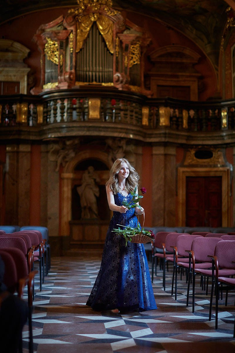 Young flower girl processing down baroque Mirror Chapel aisle.