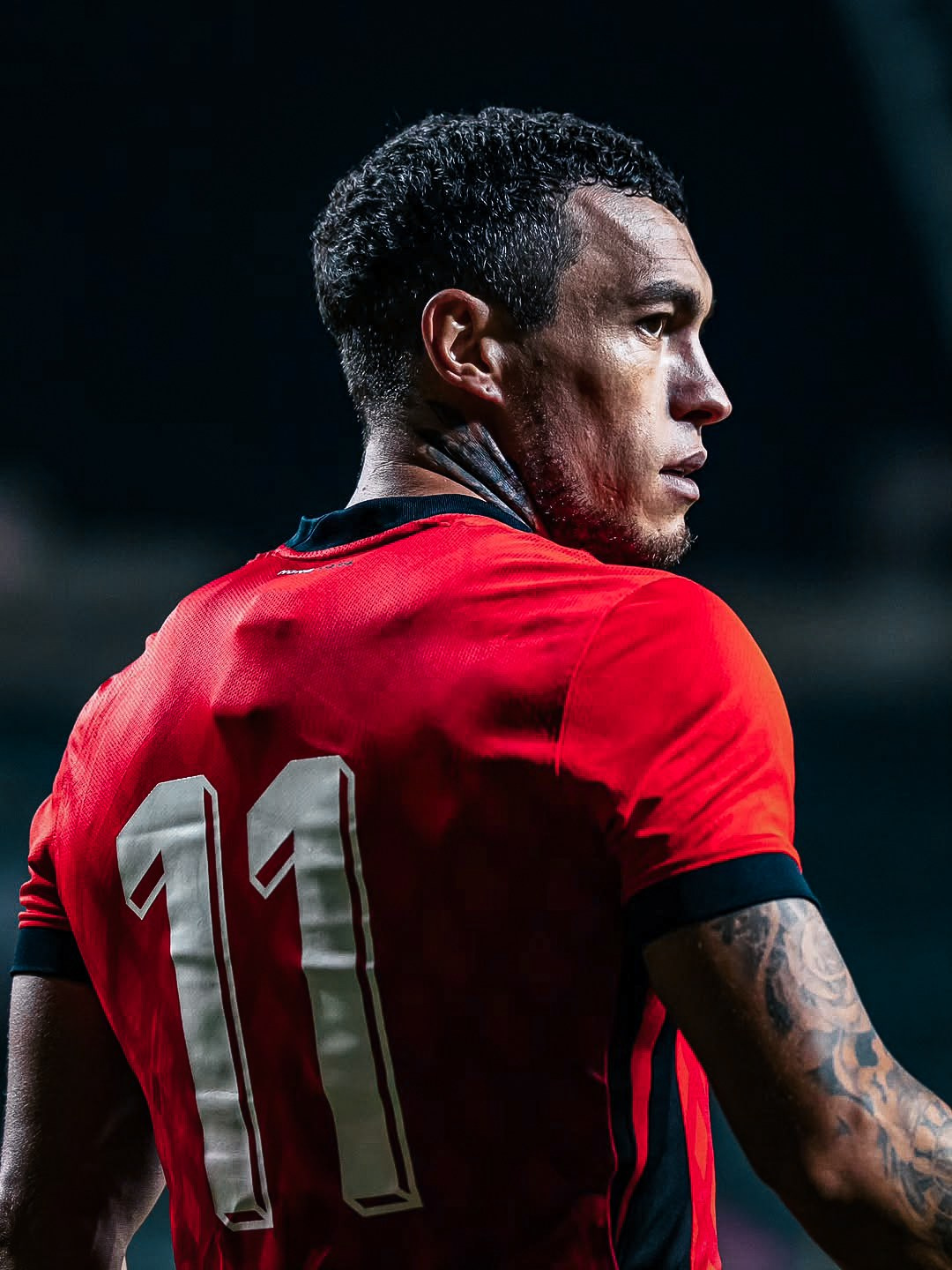 Football player wearing a red number 11 shirt during a match, cinematic football portrait photography in the UK