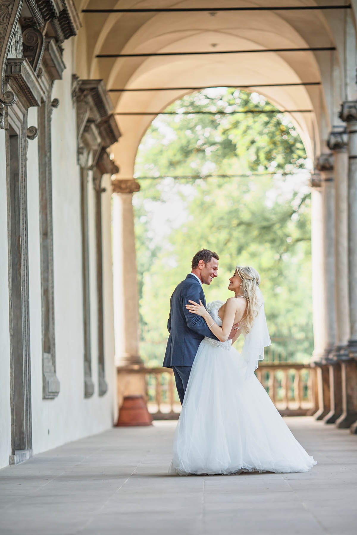 Newlyweds embracing under portico of Belvedere Queen Anne's Palace Prague