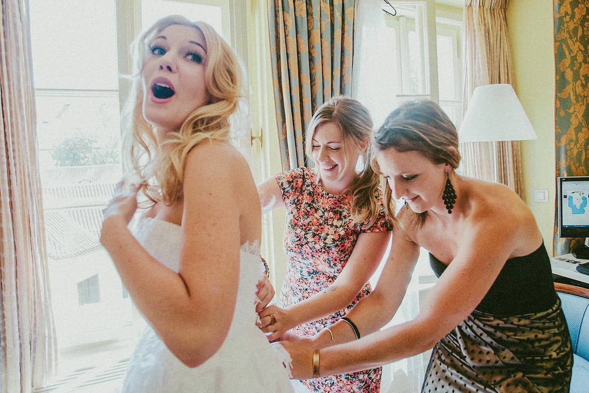 Bride Michelle is laughing as her friends help fasten her wedding dress