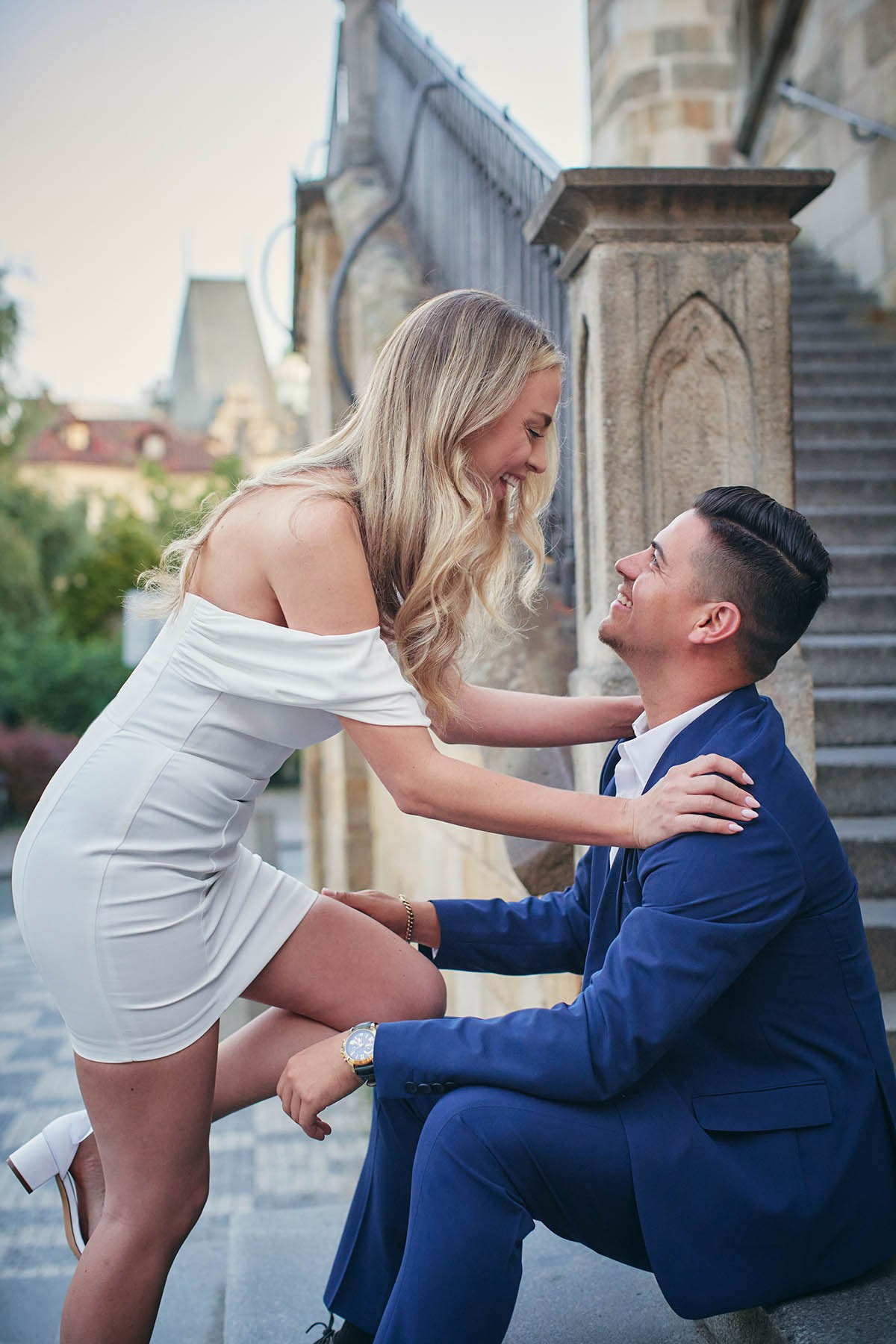 Romantic engaged pair with gentle touches on Kampa Island stone steps in soft morning glow.