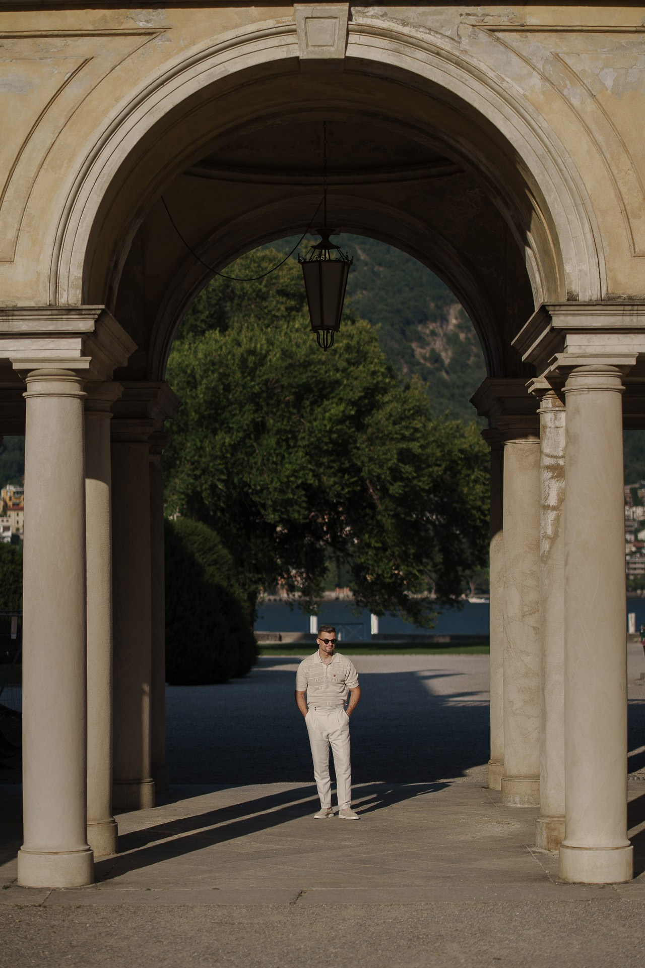 Full-length portrait beneath the historic archway at Villa Olmo in Como