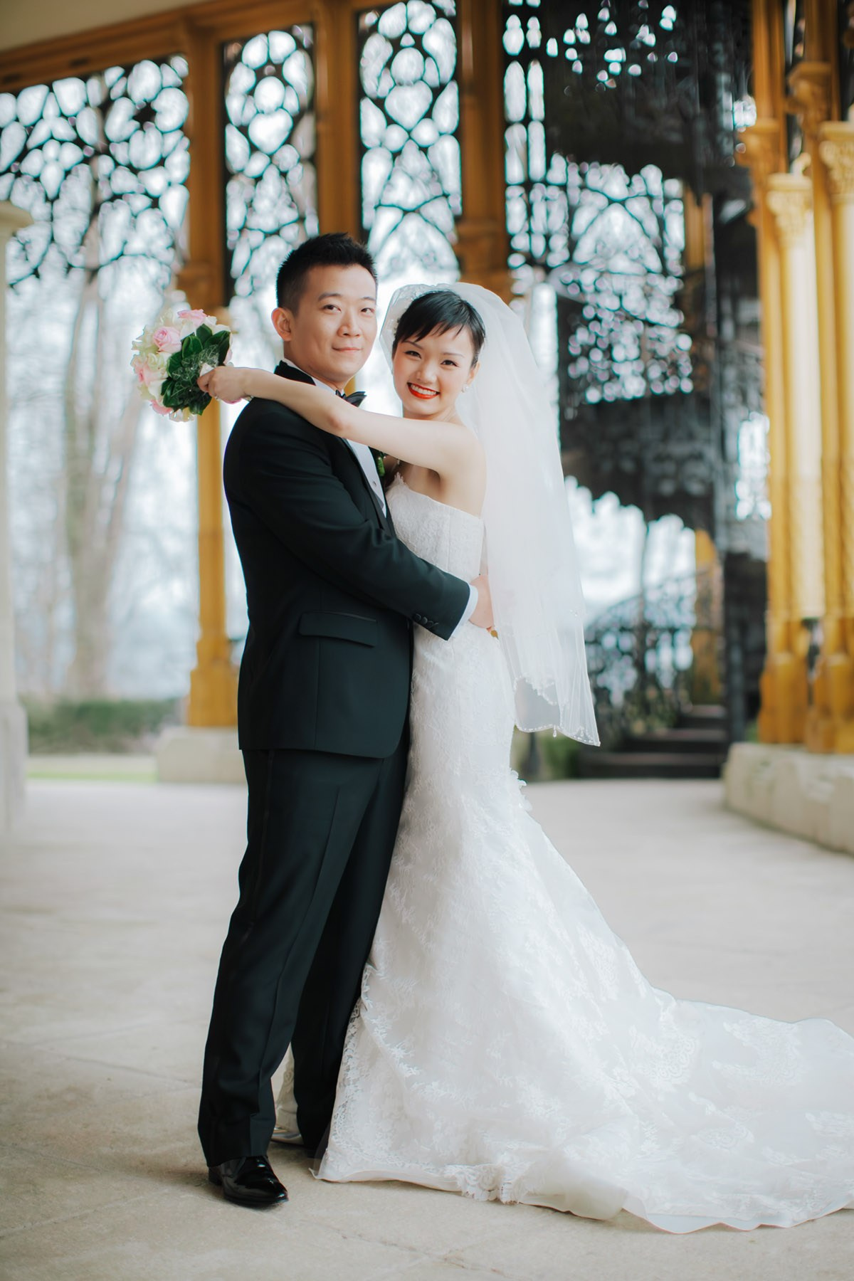 A smiling Hong Kong bride and groom pose for a photo on the historic grounds of the State Chateau of Hluboka during their destination wedding in Bohemia.