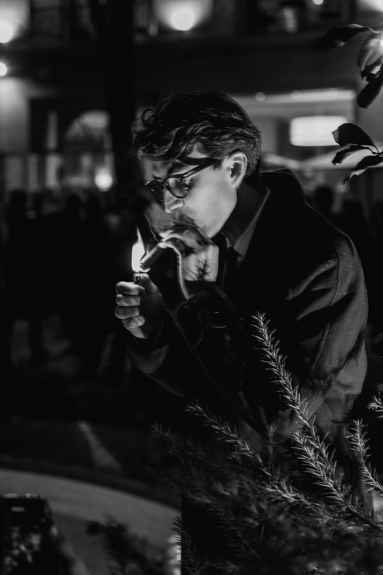 Black and white portrait of man smoking cigar during luxury evening event