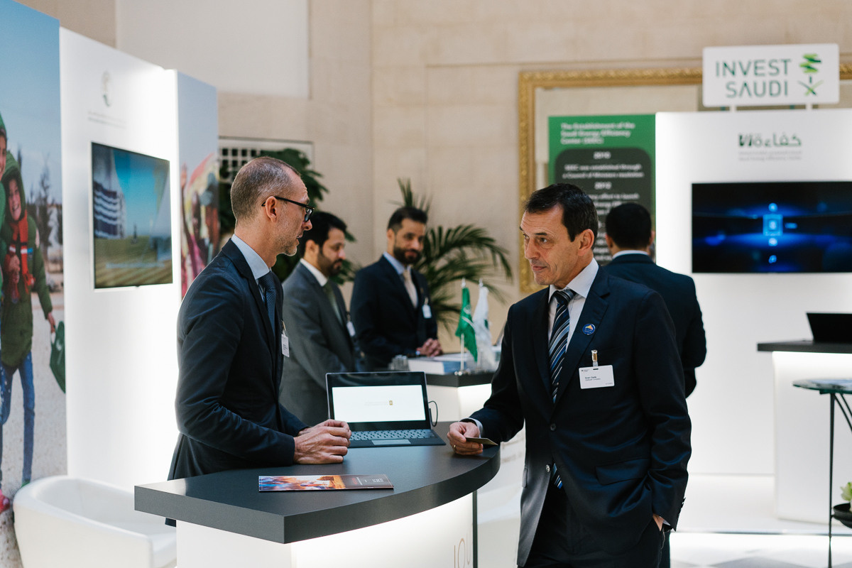 Delegates networking and exchanging ideas at information booth at international business event in the capital of Germany