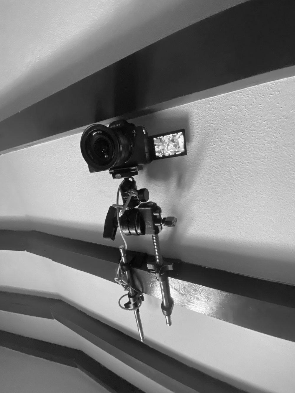 Fotografia de bastidores e equipamento a preto e branco destacando uma câmara profissional fixa num suporte, pela Khave Media