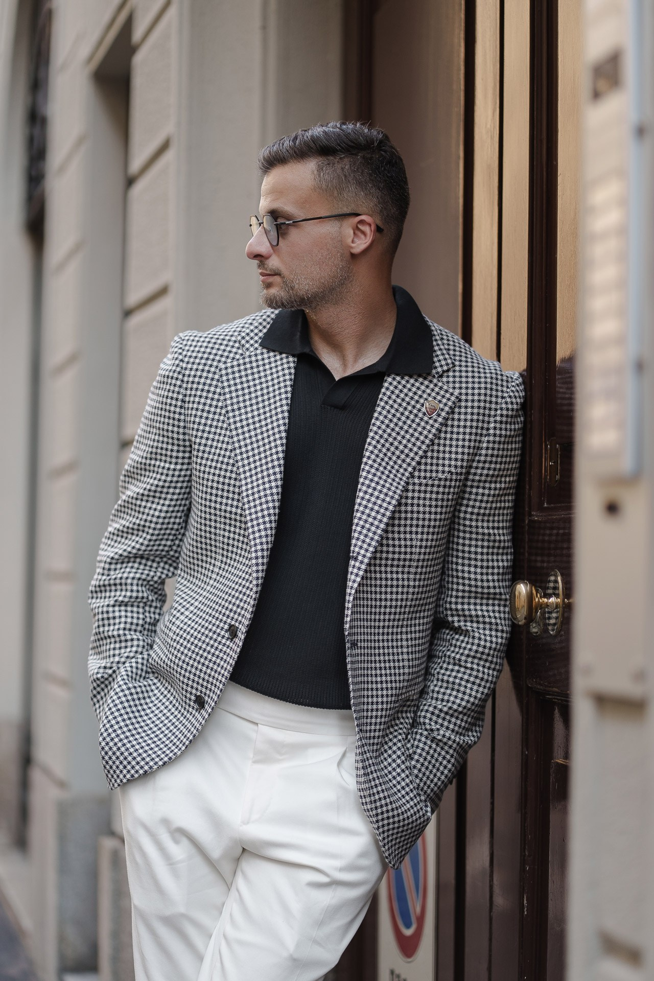 Jamal posing in a checked blazer beside an elegant doorway in Milan