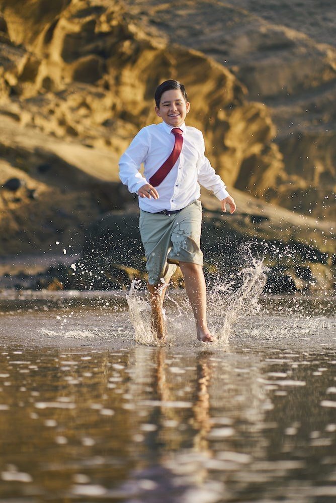 Fotos de comunión después del gran día, niño mojándose los pies en la orilla