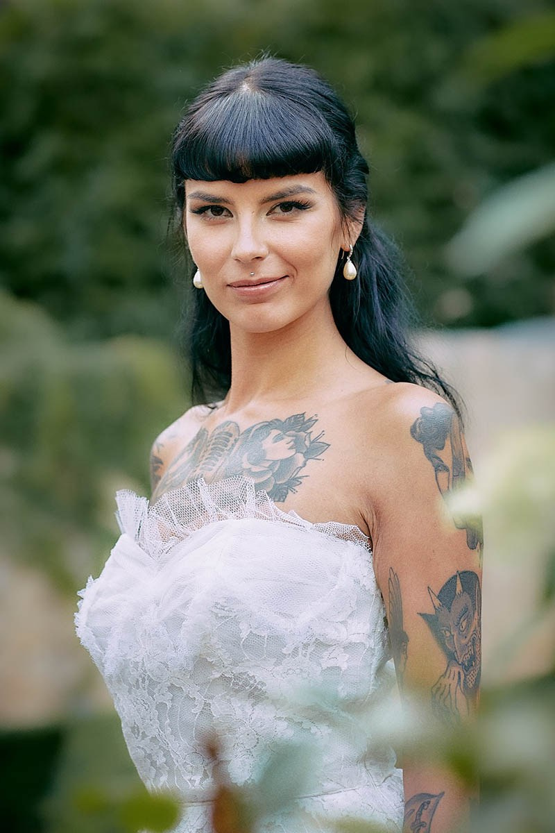 Tattooed bride elegant portrait in verdant Augustine Hotel courtyard garden.