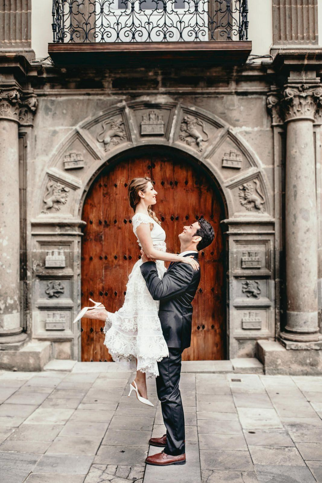 Une mariée et un marié s'embrassant devant une vieille porte.