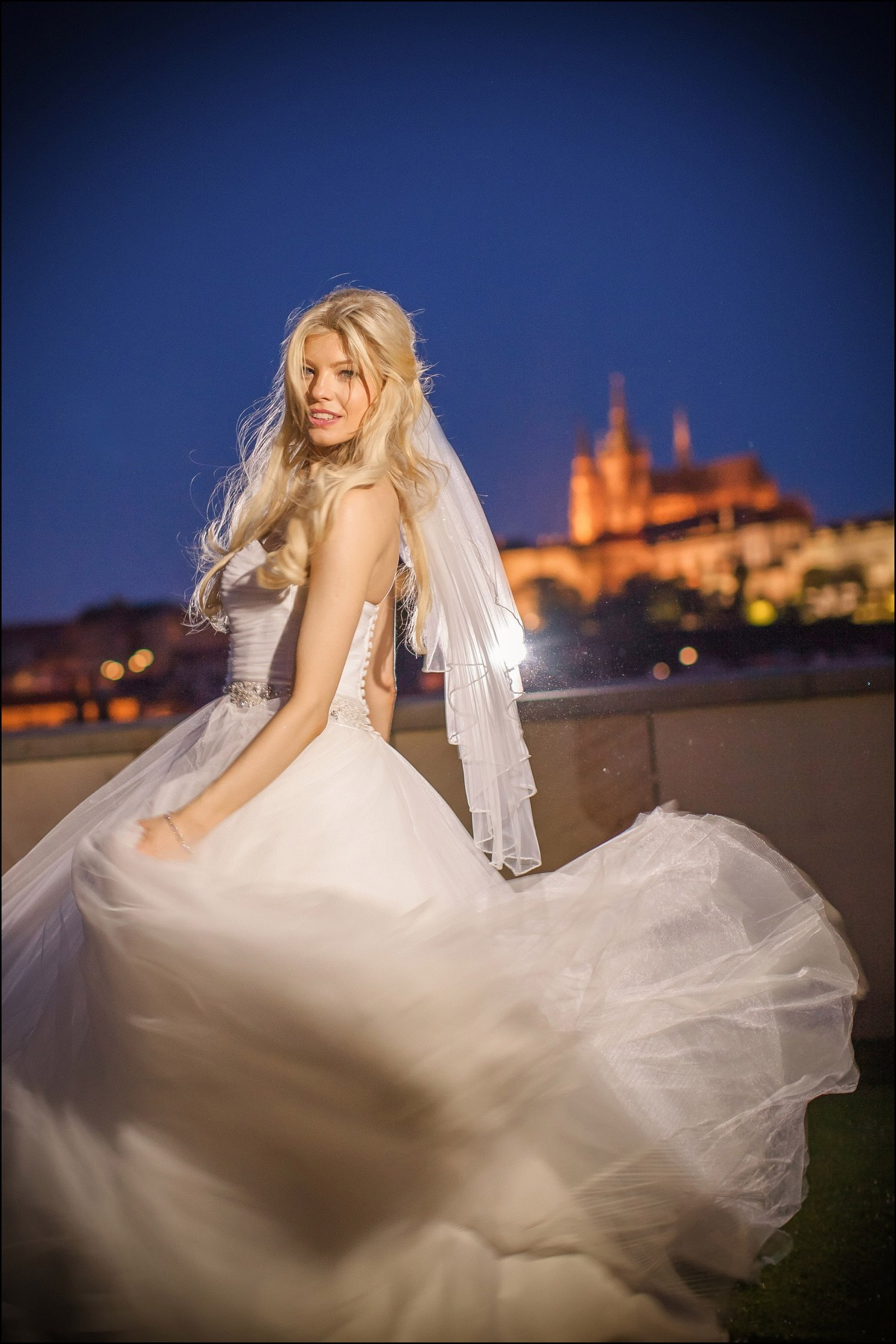 Bride twirling wedding dress nighttime Prague Castle background